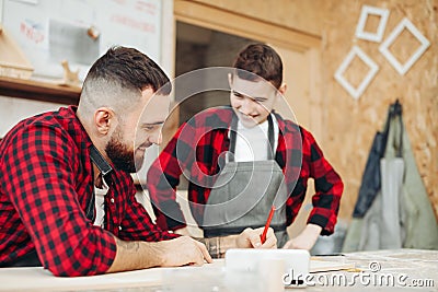 Dad and son in the workshop playing designing a model of a wooden plane Stock Photo