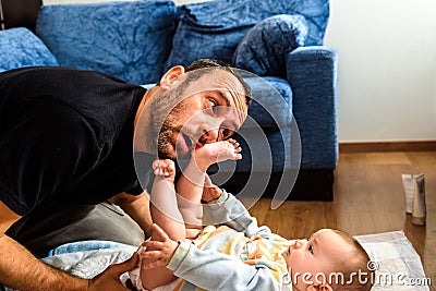 Dad struggling with his baby daughter to change dirty diapers putting faces of effort, concept of fatherhood Stock Photo
