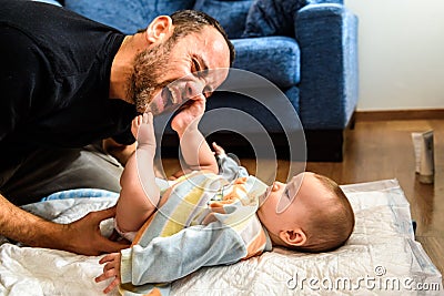 Dad struggling with his baby daughter to change dirty diapers putting faces of effort, concept of fatherhood Stock Photo