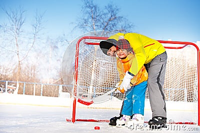 Dad teach little boy son to play ice hockey Stock Photo