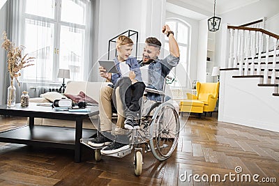 Dad in wheelchair celebrating game victory with son Stock Photo