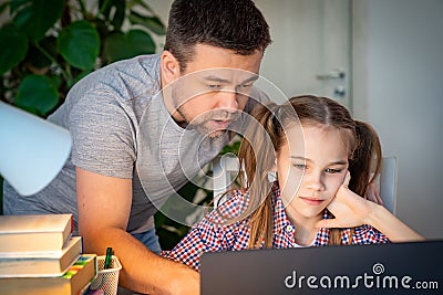 Daddy helps girl with online lessons on laptop Stock Photo