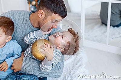 A a daddy with his two sons twins in front of the christmas tree hugging and having fun. big family concept Stock Photo