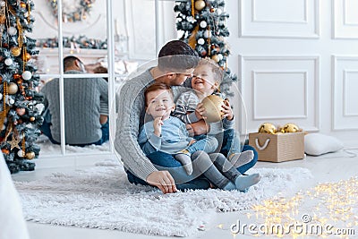 A a daddy with his two sons twins in front of the christmas tree hugging and having fun. big family concept Stock Photo