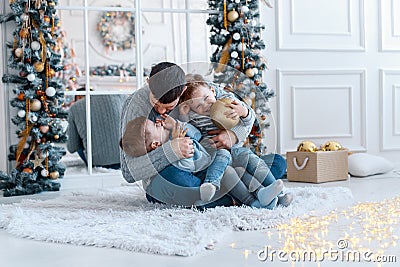 A a daddy with his two sons twins in front of the christmas tree hugging and having fun. big family concept Stock Photo