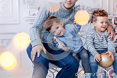 A a daddy with his two sons twins in front of the christmas tree hugging and having fun. big family concept Stock Photo