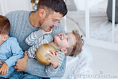 A a daddy with his two sons twins in front of the christmas tree hugging and having fun. big family concept Stock Photo