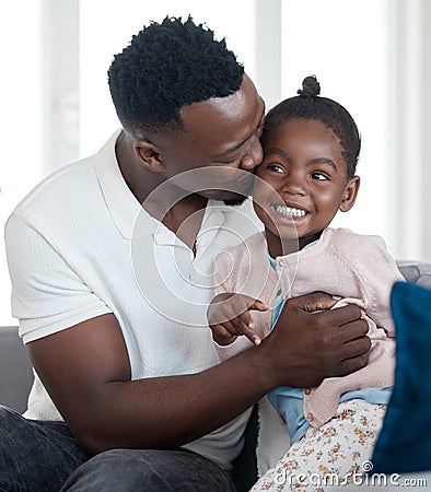 Daddy loves you. a handsome young man kissing his daughter on the cheek while relaxing in the living room at home. Stock Photo