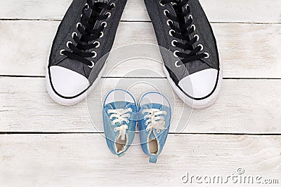 Daddy`s boots and baby`s shoes, fathers day concept. Stock Photo