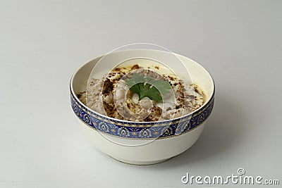 Dahi vada or bhalla is a type of chaat popular throughout Indian andSouth Asia. Dahi Bhalla bowl on white background. Stock Photo