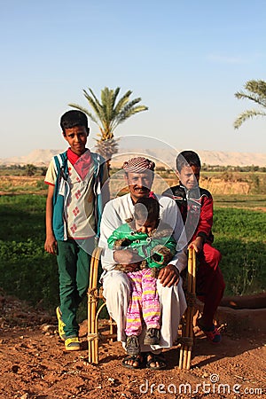 Dakhla Oasis, Egypt - April 2nd of 2015: A bedouin family posing in front of the camera with their own land backwards. Editorial Stock Photo