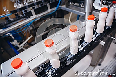 Dairy production, bottle of yoghurt on automated conveyor line, process of milk filling and packaging Stock Photo
