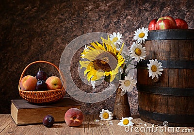 Daisy flowers in a vase with fresh fruits in a vicker basket Stock Photo