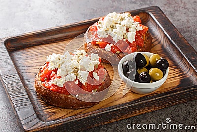 Dakos consists of a slice of cracked barley bread and garnished with crushed or grated ripe tomato and crumbled feta with oregano Stock Photo