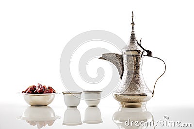 A dallah, a metal pot for making Arabic coffee with a bowl of dried dates Stock Photo