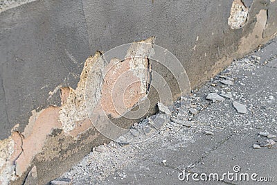 A damaged house wall and flaked exterior plaster with a large hole Stock Photo