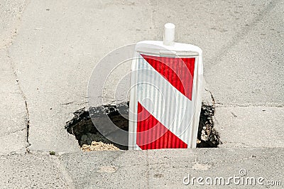 Street reconstruction or construction barricade traffic danger caution sign cover the open hole of damaged and cracked asphalt on Stock Photo