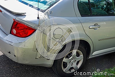 Damaged small gray car parked on a residential street. The rear panel is held on to car with adhesive tape. Editorial Stock Photo