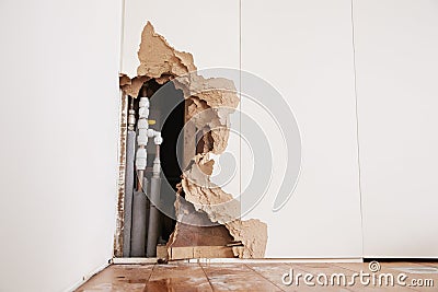 Damaged wall exposing burst water pipes after flood Stock Photo