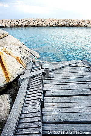 Damaged wooden pier with rock Stock Photo