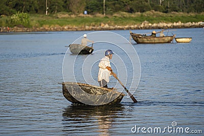 Vietnamese fisherman in a traditional round bamboo boat rowing to makeshift living rafts on the open sea near city of Danang, Editorial Stock Photo
