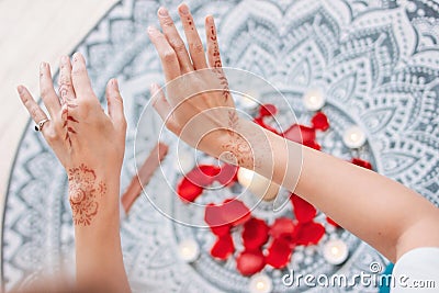 Dance of female hands with mehendi over the altar of candles and rose petals, women practices Stock Photo