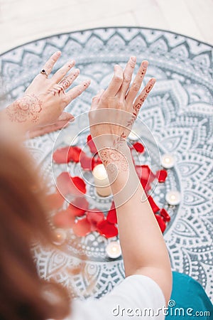 Dance of female hands with mehendi over the altar of candles and rose petals, women practices Stock Photo