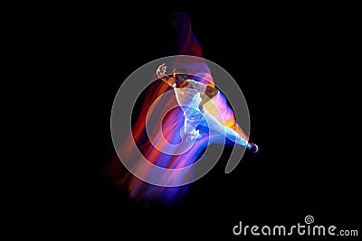 Dance in motion. Studio shot of flying, jumping dancer or gymnast performing tricks in the air over black background Stock Photo