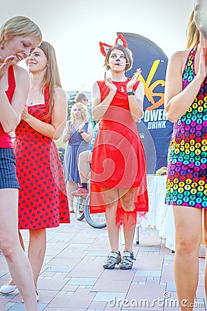 Dancing beautiful and elegant stylish girls participating in the carnival costumed women`s bike ride in the summer evening Editorial Stock Photo
