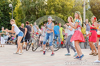 dancing beautiful and elegant stylish girls participating in the carnival costumed women`s bike ride in the summer evening Editorial Stock Photo
