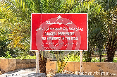 Danger - deep water and no Swimming sign in the Wadi, in Arabic and English language. Editorial Stock Photo