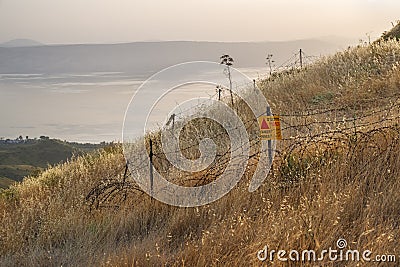 Danger mines - yellow warning sign next to a mine field, close to the border with Syria, in the Golan Heights, Israel Stock Photo