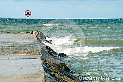 Danger, restricted area, keep off sign. Bright red and white public warning sign at a rocky coastline. Swimming restriction area. Stock Photo