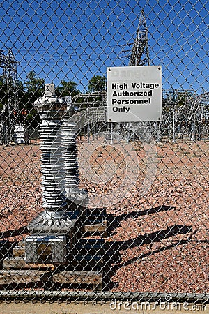 A `Danger` sign in front of a fence of a utility company Stock Photo