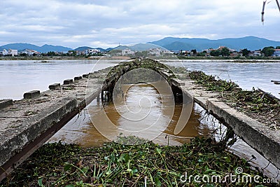 Damaged bridge across flowing river Stock Photo