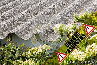 Dangerous asbestos roof concept with the message danger asbestos written on a yellow stripe Stock Photo