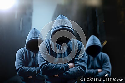 Dangerous criminal. Scary hooded guys at night in dark alley. silhouette bandit, criminal with an unrecognizable face in Stock Photo