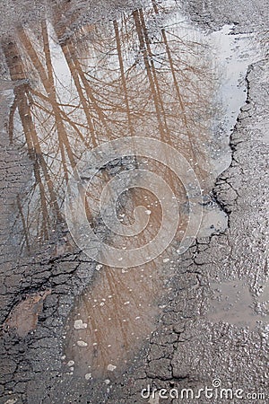 Dangerous destroyed roadbed. The bad asphalted road. Big pothole filled with water. Stock Photo