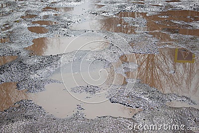 Dangerous destroyed roadbed. Big pothole filled with water. Stock Photo