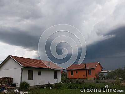Dangerous dramatic dark clouds above settlement, ominous stormy weather with rain during summer Editorial Stock Photo