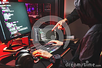 Dangerous Hooded Hacker typing bad data into computer online system and spreading to global stolen personal information. Cyber Stock Photo