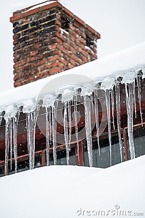 Dangerous sharp icicles and snow hanging from the roof Stock Photo