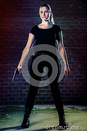 Dangerous woman terrorist dressed in black with a gun in her han Stock Photo