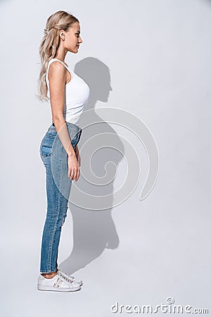 Dangerously beautiful. Full length portrait of Attractive young woman stands in profile and smiling while standing against grey Stock Photo