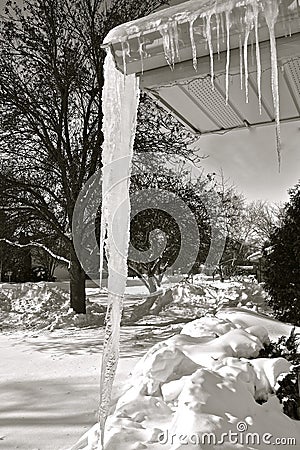 Dangerously huge icicle hanging from an eavestrough Stock Photo