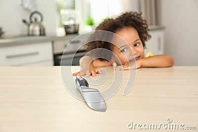 Dangers in kitchen. African American girl reaching after knife at table Stock Photo