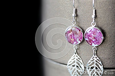 Dangle resin earrings with rose petals on a dark background Stock Photo