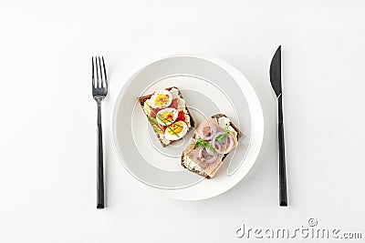 Danish smorrebrod open sandwiches on white plate, fork and knife on white background Stock Photo