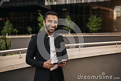 Dapper smiling indian muslim businessman holding tablet outside Stock Photo