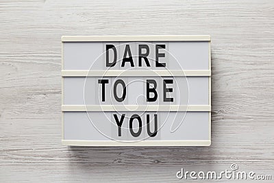 `Dare to be you` on a lightbox on a white wooden surface, top view. Flat lay, overhead, from above Stock Photo